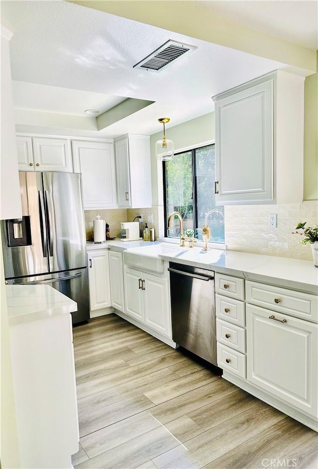 3931 Cottonwood Grove Trl, Calabasas, CA 91301 - kitchen with appliances with stainless steel finishes, white cabinets, tasteful backsplash, and pendant lighting