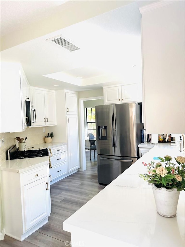 3931 Cottonwood Grove Trl, Calabasas, CA 91301 - kitchen with stainless steel appliances, light wood-style flooring, white cabinets, tasteful backsplash, and light stone counters