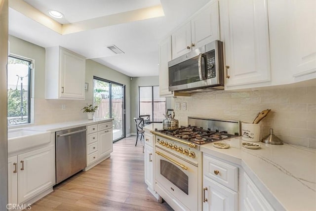 3931 Cottonwood Grove Trl, Calabasas, CA 91301 - kitchen featuring stainless steel appliances, white cabinetry, a tray ceiling, decorative backsplash, and recessed lighting