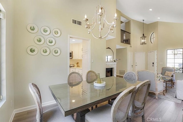 3931 Cottonwood Grove Trl, Calabasas, CA 91301 - dining area featuring a chandelier, a towering ceiling, wood finished floors, a fireplace, and recessed lighting