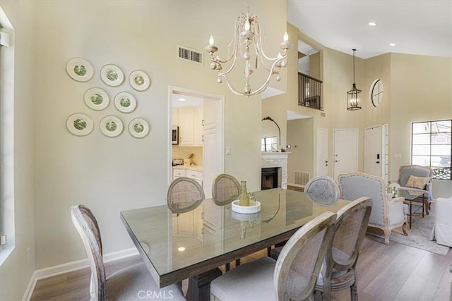 3931 Cottonwood Grove Trl, Calabasas, CA 91301 - dining room featuring a chandelier, a high ceiling, wood finished floors, a fireplace, and recessed lighting