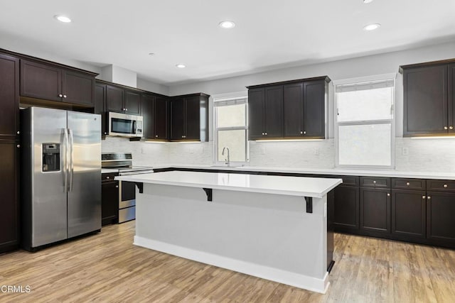 623 W Foothill Blvd Unit 43, Glendora, CA 91741 - kitchen featuring appliances with stainless steel finishes, a breakfast bar area, a kitchen island, light countertops, and light wood finished floors