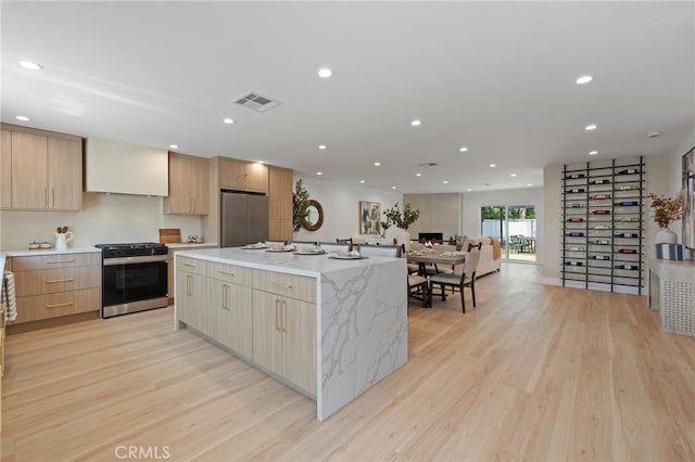 8840 Valjean Ave, North Hills, CA 91343 - kitchen featuring appliances with stainless steel finishes, modern cabinets, light wood-type flooring, light brown cabinets, and a spacious island