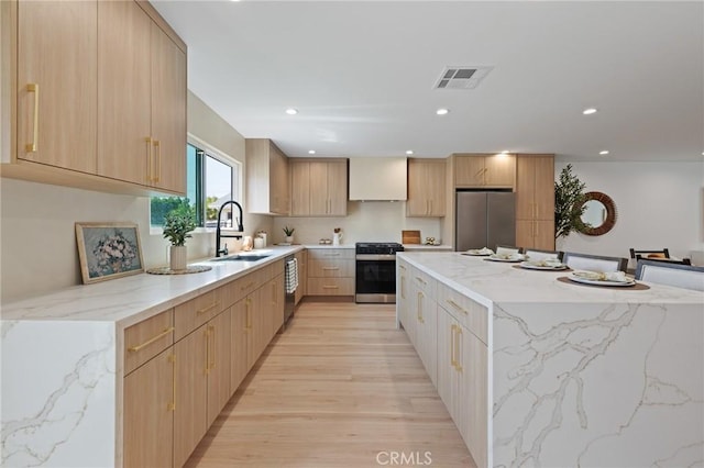 8840 Valjean Ave, North Hills, CA 91343 - kitchen featuring appliances with stainless steel finishes, light wood-style flooring, a spacious island, light stone counters, and premium range hood