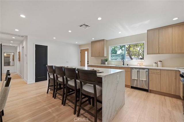 8840 Valjean Ave, North Hills, CA 91343 - kitchen with stainless steel dishwasher, light wood finished floors, light brown cabinetry, a kitchen breakfast bar, and recessed lighting