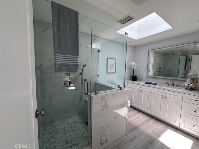 13361 El Dorado Unit 201K, Seal Beach, CA 90740 - full bath featuring a skylight, a marble finish shower, vanity, wood finished floors, and a garden tub