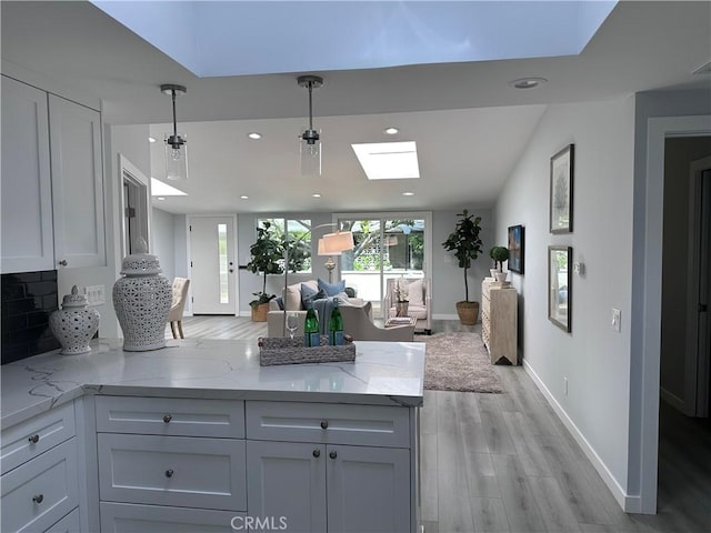 13361 El Dorado Unit 201K, Seal Beach, CA 90740 - kitchen with open floor plan, a peninsula, recessed lighting, light wood-style floors, and light stone counters