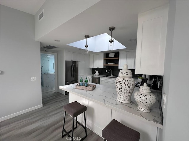13361 El Dorado Unit 201K, Seal Beach, CA 90740 - kitchen featuring stainless steel dishwasher, a peninsula, open shelves, light stone countertops, and freestanding refrigerator