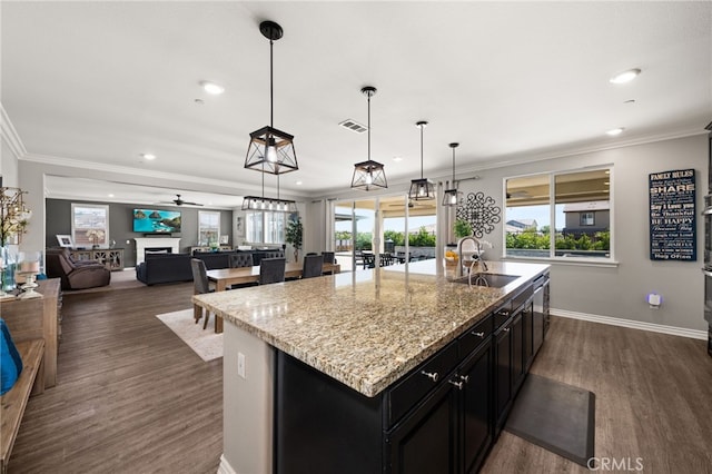 16671 Zest Ct, Riverside, CA 92503 - kitchen featuring dark cabinetry, an island with sink, dark wood-type flooring, ornamental molding, and healthy amount of natural light