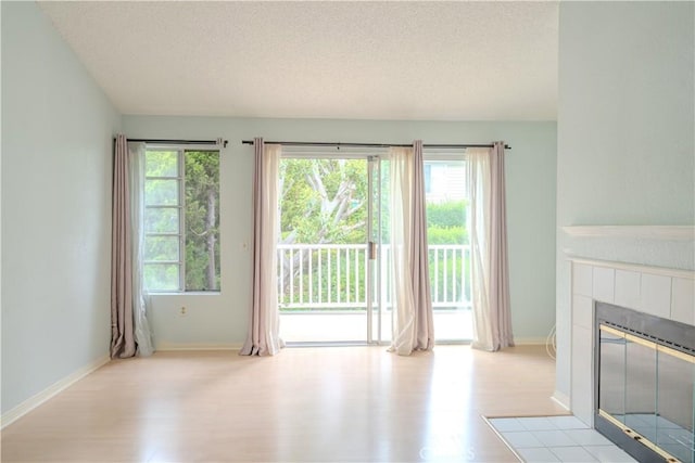 1430 Brett Pl Unit 12, San Pedro, CA 90732 - unfurnished living room featuring wood finished floors, a textured ceiling, and a tiled fireplace