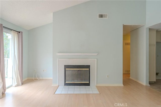 1430 Brett Pl Unit 12, San Pedro, CA 90732 - unfurnished living room with wood finished floors, a tile fireplace, vaulted ceiling, and a textured ceiling