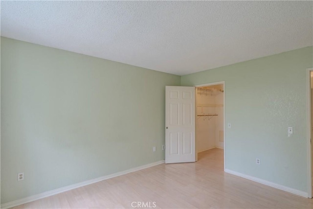 1430 Brett Pl Unit 12, San Pedro, CA 90732 - unfurnished bedroom with a walk in closet, light wood-style floors, a textured ceiling, and a closet
