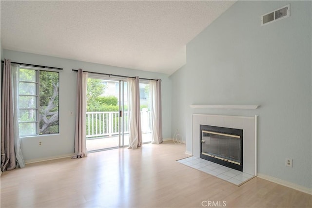 1430 Brett Pl Unit 12, San Pedro, CA 90732 - unfurnished living room with wood finished floors, a textured ceiling, a tiled fireplace, and lofted ceiling