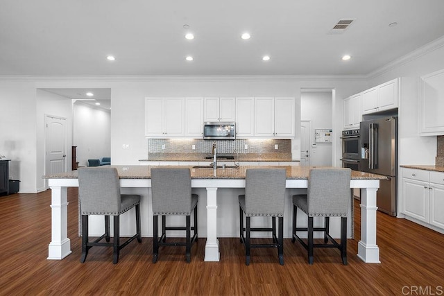 1837 Ashley Ave, Chula Vista, CA 91913 - kitchen featuring appliances with stainless steel finishes, crown molding, dark wood-type flooring, white cabinetry, and decorative backsplash