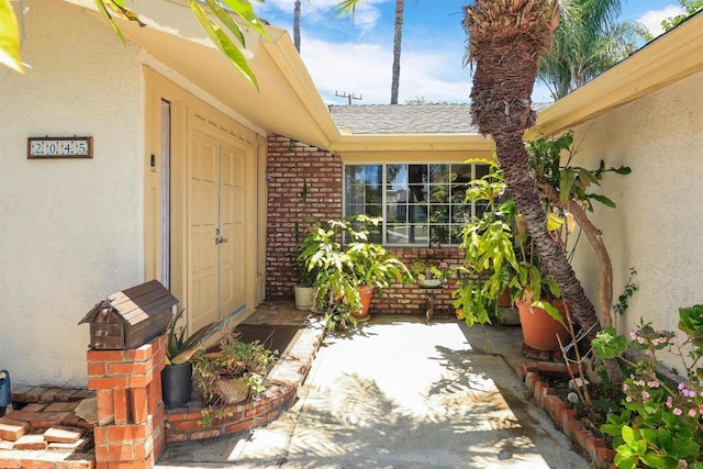 2045 W Clover Ave, Anaheim, CA 92801 - doorway to property featuring brick siding, roof with shingles, and stucco siding