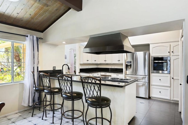 2045 W Clover Ave, Anaheim, CA 92801 - kitchen featuring wall chimney exhaust hood, appliances with stainless steel finishes, dark countertops, a peninsula, and white cabinetry