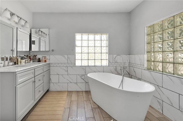10325 Sheep Creek Rd, Phelan, CA 92371 - full bathroom with tile walls, healthy amount of natural light, double vanity, a freestanding bath, and a wainscoted wall