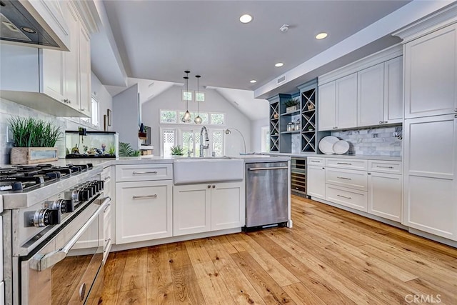 1310 Gates Ave, Manhattan Beach, CA 90266 - kitchen featuring appliances with stainless steel finishes, ventilation hood, a peninsula, light wood-style flooring, and vaulted ceiling
