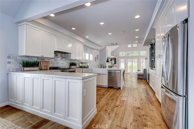 1310 Gates Ave, Manhattan Beach, CA 90266 - kitchen with appliances with stainless steel finishes, a peninsula, light wood-style flooring, white cabinetry, and light countertops