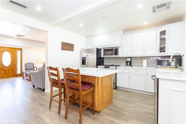 6843 Penfield Ave, Winnetka, CA 91306 - kitchen with stainless steel appliances, light wood-style flooring, a kitchen island, backsplash, and recessed lighting