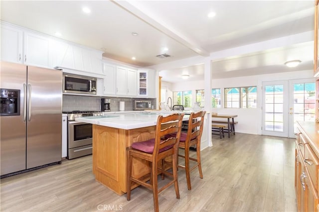 6843 Penfield Ave, Winnetka, CA 91306 - kitchen with stainless steel appliances, light wood-style floors, light countertops, a kitchen breakfast bar, and beam ceiling