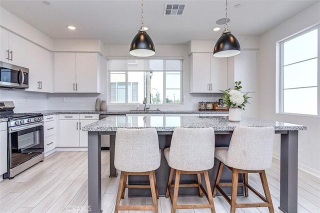 14180 Bay St, La Mirada, CA 90638 - kitchen with appliances with stainless steel finishes, tasteful backsplash, hanging light fixtures, a breakfast bar area, and recessed lighting