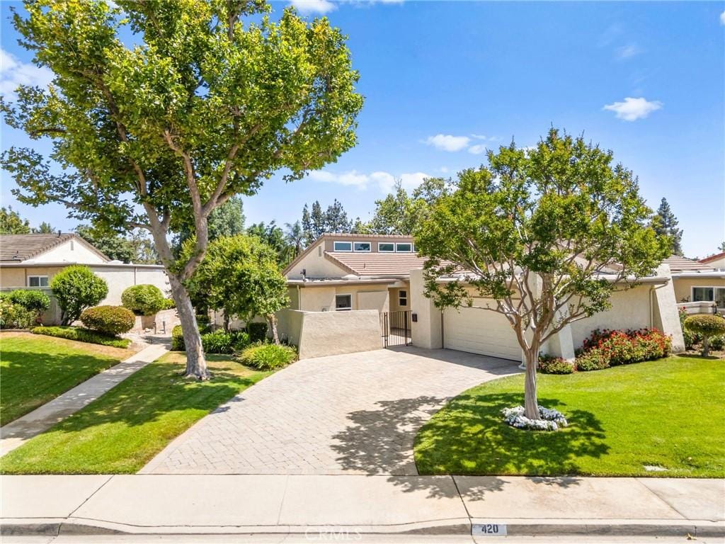 420 Champlain Dr, Claremont, CA 91711 - mid-century home with decorative driveway, an attached garage, a front lawn, and stucco siding
