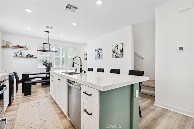 10 Wisteria St, Rancho Mission Viejo, CA 92694 - kitchen featuring appliances with stainless steel finishes, white cabinetry, light wood finished floors, a breakfast bar, and light countertops