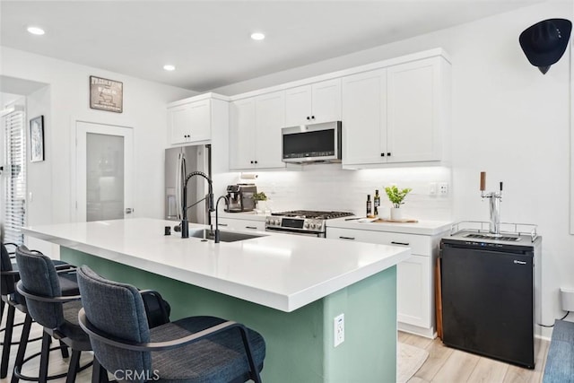 10 Wisteria St, Rancho Mission Viejo, CA 92694 - kitchen with stainless steel appliances, light wood-type flooring, white cabinets, a kitchen bar, and decorative backsplash