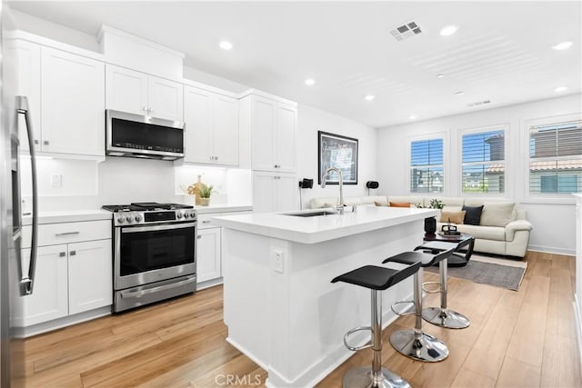 112 Juniper Dr, Rancho Mission Viejo, CA 92694 - kitchen featuring appliances with stainless steel finishes, a breakfast bar, light wood finished floors, open floor plan, and white cabinetry
