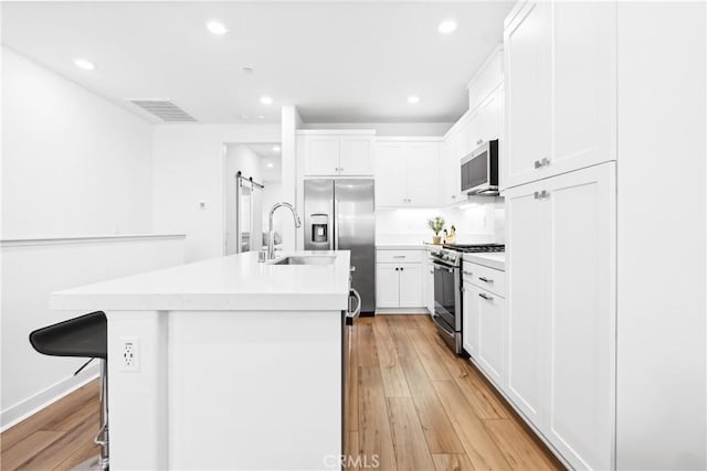 112 Juniper Dr, Rancho Mission Viejo, CA 92694 - kitchen with appliances with stainless steel finishes, recessed lighting, white cabinets, a kitchen island with sink, and light wood finished floors