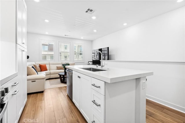 112 Juniper Dr, Rancho Mission Viejo, CA 92694 - kitchen with light countertops, white cabinets, light wood-type flooring, open floor plan, and a kitchen island with sink