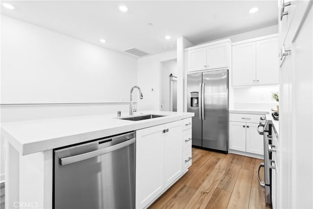 112 Juniper Dr, Rancho Mission Viejo, CA 92694 - kitchen with appliances with stainless steel finishes, light wood finished floors, recessed lighting, white cabinets, and a center island with sink