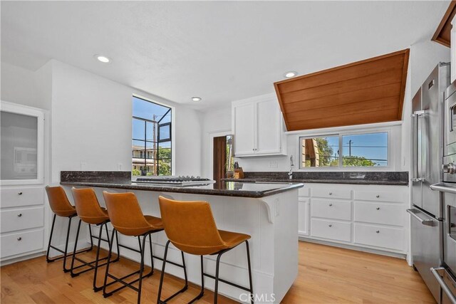 390 Saint Anns Dr, Laguna Beach, CA 92651 - kitchen featuring light wood-style floors, white cabinetry, a breakfast bar, a peninsula, and recessed lighting