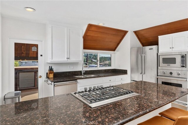 390 Saint Anns Dr, Laguna Beach, CA 92651 - kitchen featuring stainless steel appliances, white cabinets, dark stone countertops, recessed lighting, and vaulted ceiling