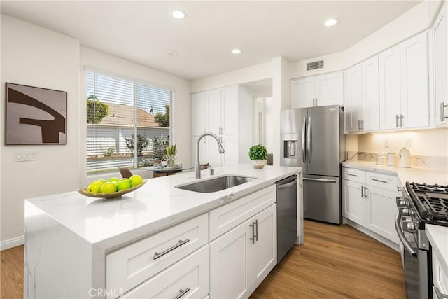 17 Marseille Way, Lake Forest, CA 92610 - kitchen with appliances with stainless steel finishes, white cabinetry, light stone counters, recessed lighting, and light wood-type flooring