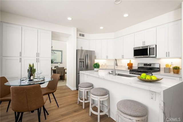 17 Marseille Way, Lake Forest, CA 92610 - kitchen with appliances with stainless steel finishes, a breakfast bar area, light wood-type flooring, white cabinets, and recessed lighting