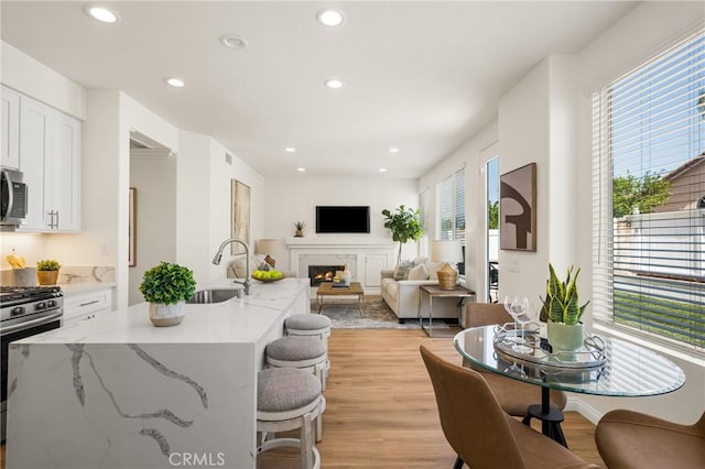 17 Marseille Way, Lake Forest, CA 92610 - kitchen with stainless steel appliances, light wood-style flooring, recessed lighting, white cabinets, and a lit fireplace