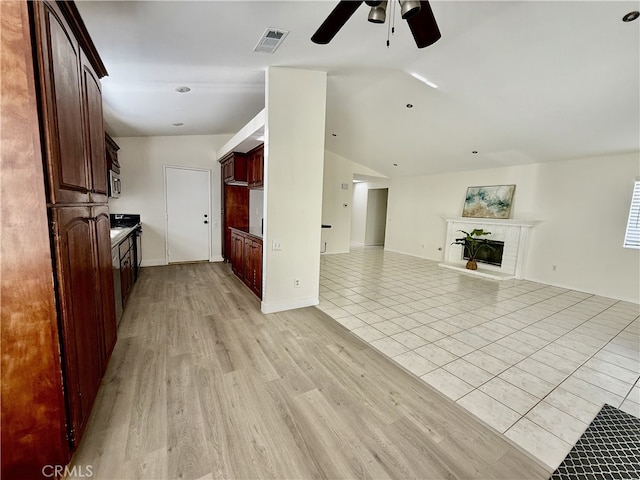 1350 William Mcgrath St, Colton, CA 92324 - unfurnished living room featuring ceiling fan, vaulted ceiling, a fireplace with raised hearth, and light wood finished floors