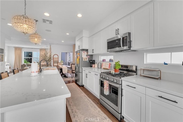 516 Caleigh Ln, Costa Mesa, CA 92627 - kitchen with stainless steel appliances, a chandelier, a kitchen island with sink, dark wood-type flooring, and light countertops