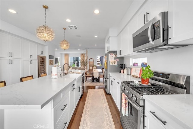 516 Caleigh Ln, Costa Mesa, CA 92627 - kitchen with appliances with stainless steel finishes, recessed lighting, dark wood-style floors, a spacious island, and white cabinetry