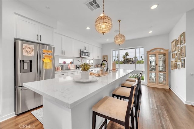 516 Caleigh Ln, Costa Mesa, CA 92627 - kitchen featuring stainless steel appliances, a breakfast bar, recessed lighting, an island with sink, and white cabinetry