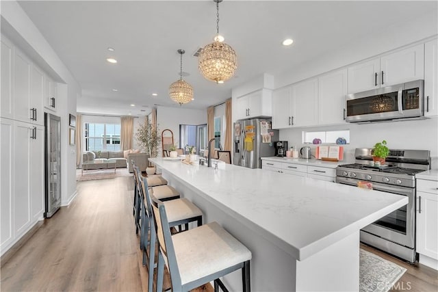 516 Caleigh Ln, Costa Mesa, CA 92627 - kitchen with appliances with stainless steel finishes, recessed lighting, open floor plan, a chandelier, and white cabinets