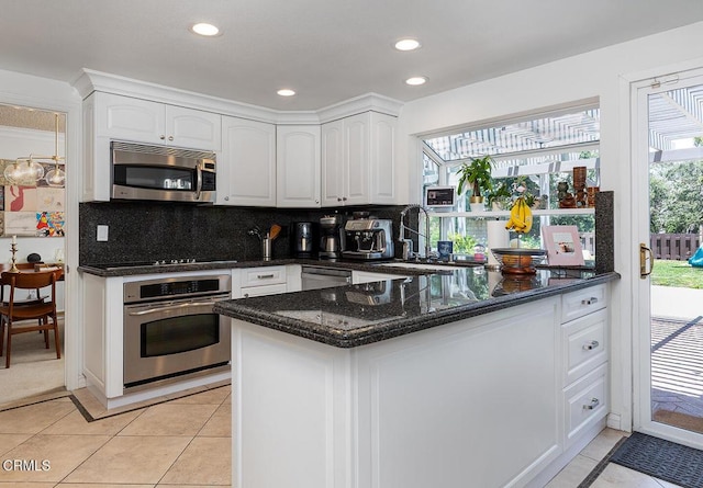 18845 Braemore Rd, Porter Ranch, CA 91326 - kitchen with appliances with stainless steel finishes, dark stone counters, white cabinetry, decorative backsplash, and light tile patterned floors