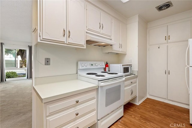 2179 Via Puerta Unit R, Laguna Woods, CA 92637 - kitchen with white appliances, under cabinet range hood, white cabinets, and light countertops