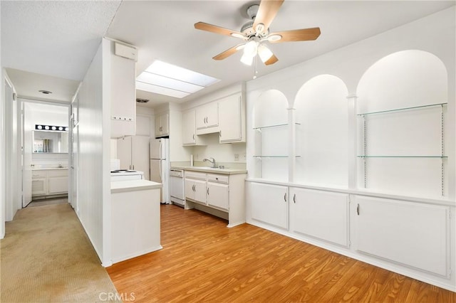 2179 Via Puerta Unit R, Laguna Woods, CA 92637 - kitchen with white appliances, ceiling fan, light countertops, white cabinets, and light wood-style floors