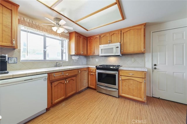 35632 Avocado St, Yucaipa, CA 92399 - kitchen featuring white appliances, light wood-style floors, tile countertops, a ceiling fan, and tasteful backsplash