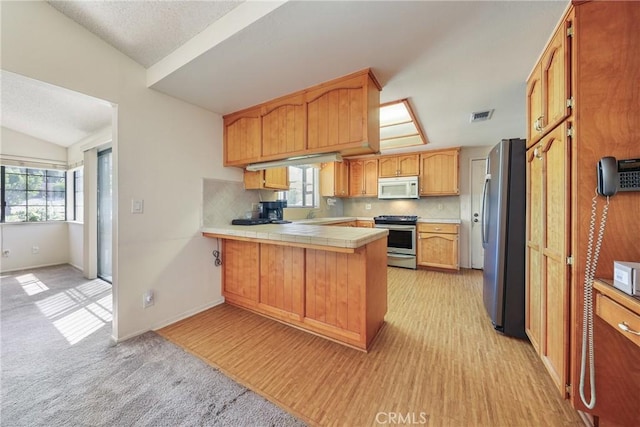 35632 Avocado St, Yucaipa, CA 92399 - kitchen with stainless steel appliances, a peninsula, decorative backsplash, lofted ceiling, and tile countertops