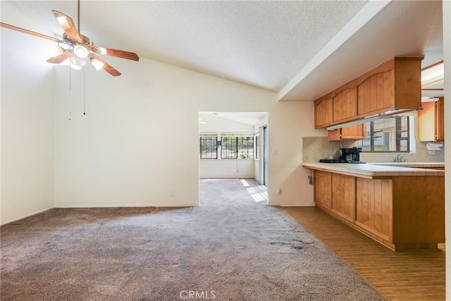 35632 Avocado St, Yucaipa, CA 92399 - kitchen with tile countertops, lofted ceiling, a ceiling fan, brown cabinetry, and decorative backsplash
