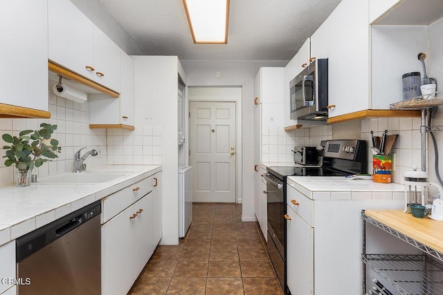 377 W California Ave, Glendale, CA 91203 - kitchen with appliances with stainless steel finishes, tile counters, white cabinets, and backsplash